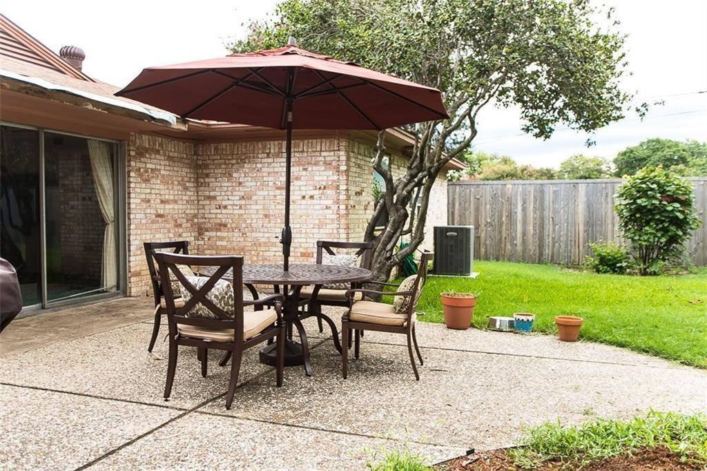 Concrete patio featuring a brick exterior wall, sliding glass doors, and a wood privacy fence