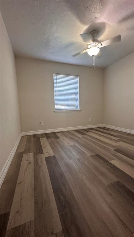 Room featuring wood-finish flooring, a neutral color palette, a window with horizontal blinds, and a ceiling-mounted light fixture with a fan