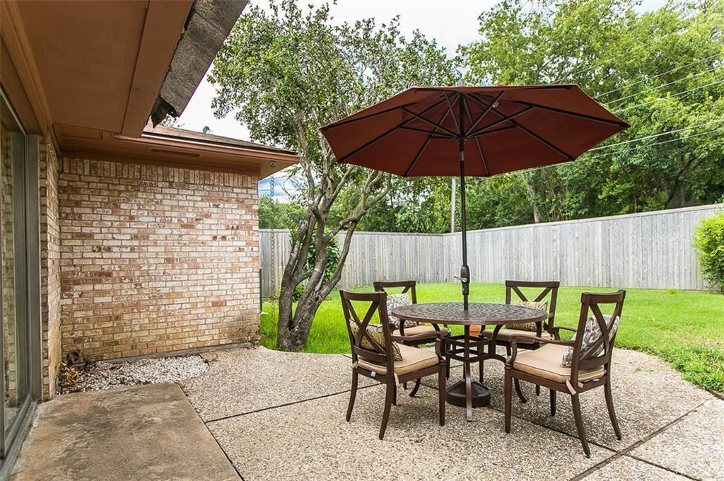 Concrete patio with brick exterior wall, mature trees, and wooden privacy fencing