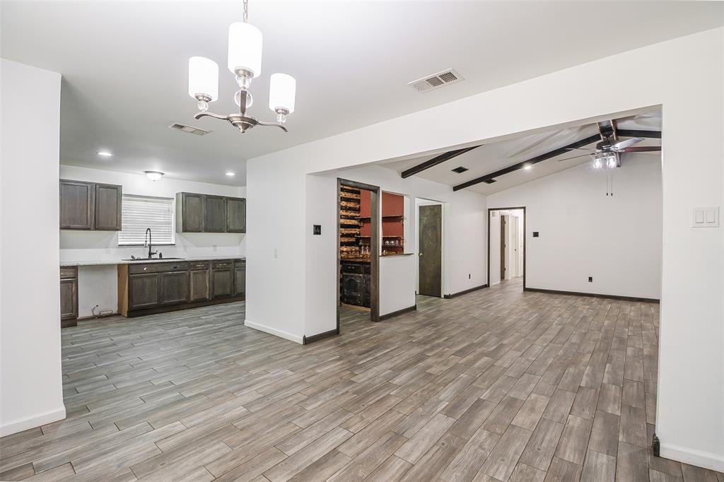 Kitchen featuring stained wood cabinetry, white countertops, and a pendant chandelier, complemented by wood-finish flooring throughout the interior with exposed ceiling beams