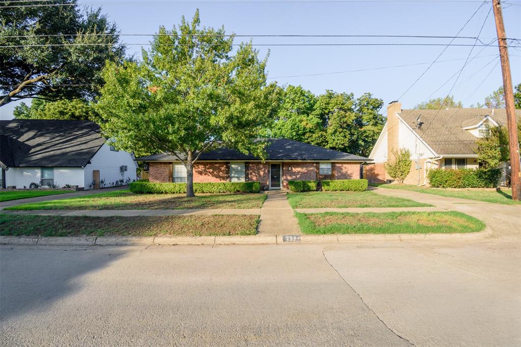 Single-story brick exterior featuring a low-pitch roof, mature landscaping, and a centered concrete walkway Single-story brick exterior featuring a low-pitch roof, mature landscaping, and a centered concrete walkway
