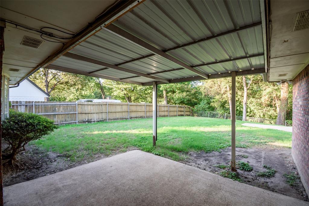 Covered patio with a metal roof, concrete flooring, brick exterior wall, and fenced backyard