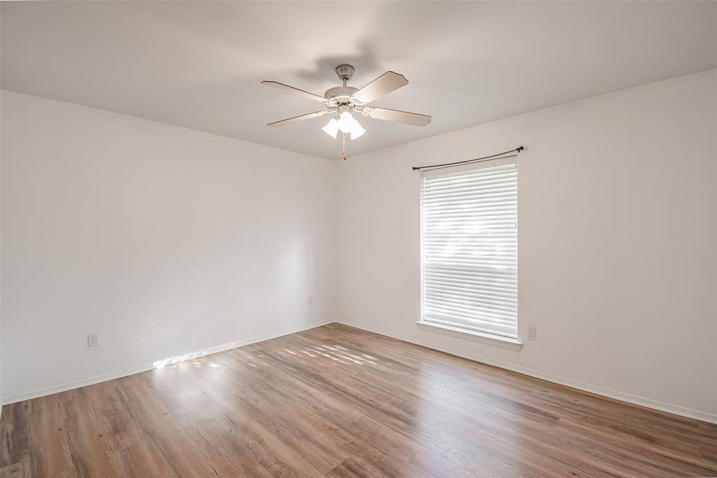 Room featuring wood-finish flooring, a ceiling fan with integrated lighting, and a window with horizontal blinds