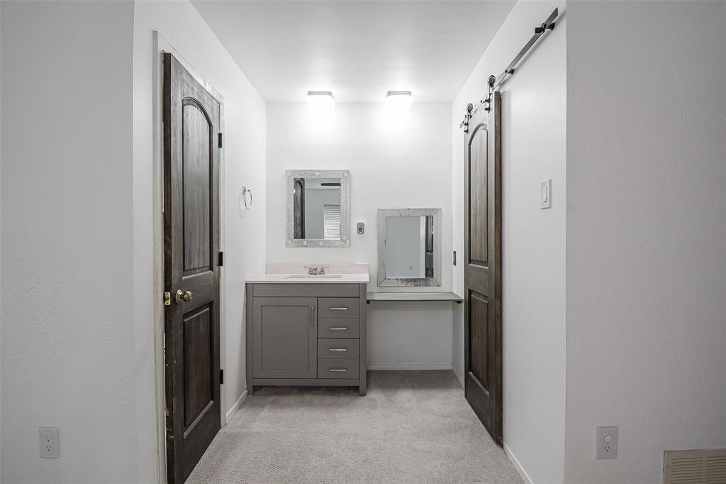 Grey vanity with countertop, integrated sink, and built-in storage, side counter extension, and dark wood-finish doors