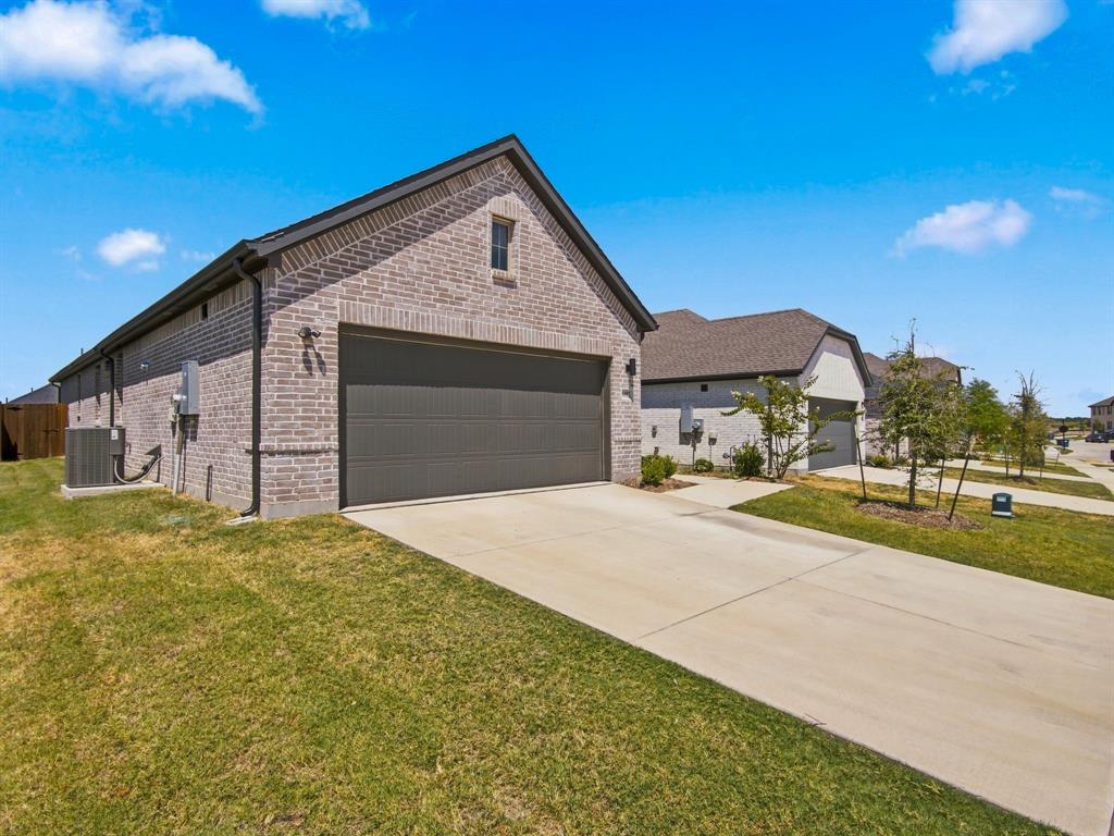 Brick exterior, gabled roofline, concrete driveway, and attached two-car garage
