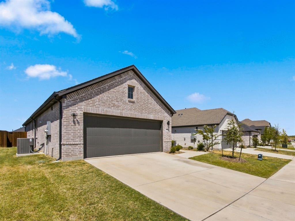 Brick exterior featuring a gabled roofline, a two-car garage with a paneled door, and a concrete driveway