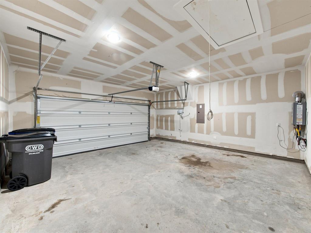 Attached garage featuring a concrete floor, an overhead sectional garage door, flush-mount ceiling lighting, and an attic access panel