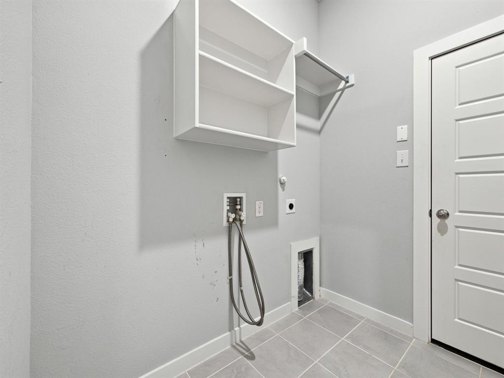 Utility space featuring tile flooring, built-in shelving, a garment rod, and washer and dryer hookups