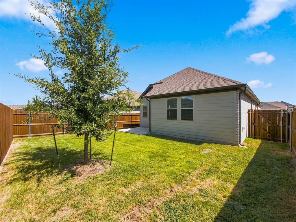 Backyard featuring a grass lawn, mature tree, concrete patio, and full-height wood fencing