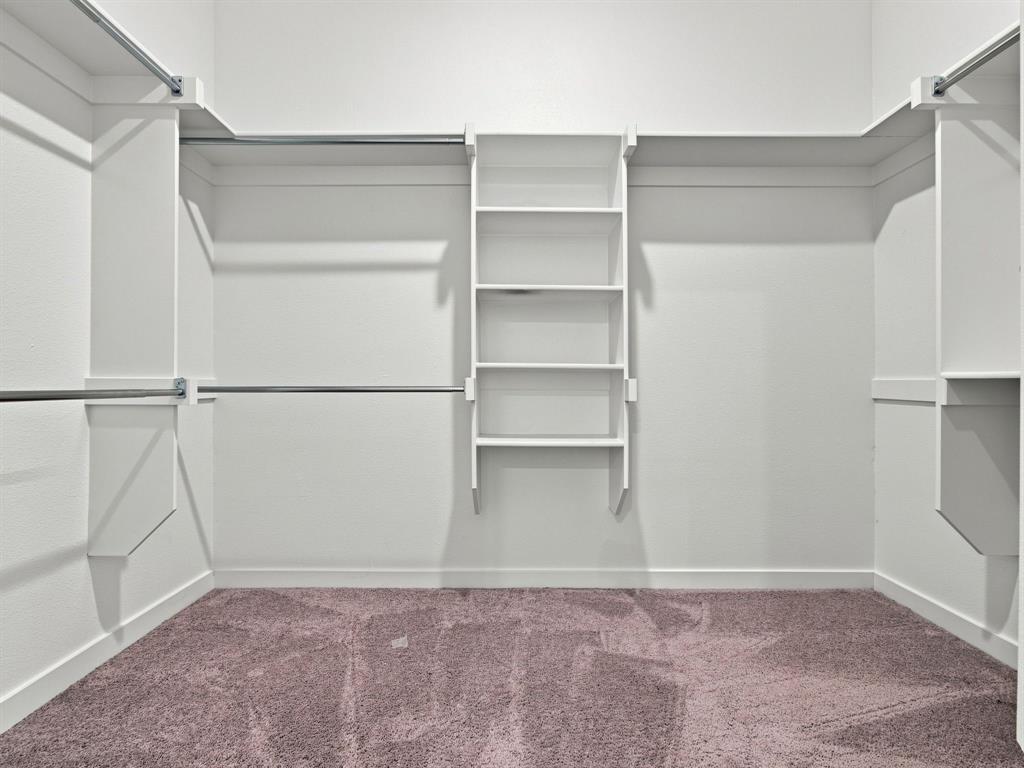 Walk-in closet featuring white built-in shelving, adjustable storage racks, and wall-to-wall carpeting