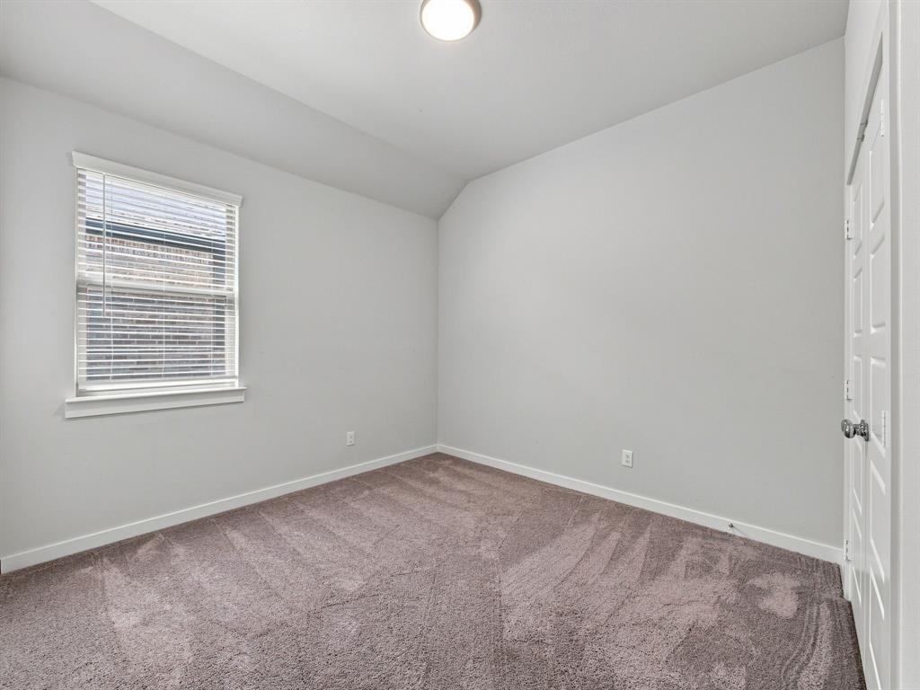Neutral-toned room featuring plush wall-to-wall carpeting, a vaulted ceiling, a single-hung window with horizontal blinds, and a paneled closet door