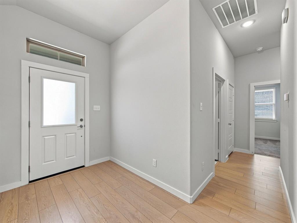 Entryway featuring wood-finish flooring, high ceilings, a door with a glass insert, and a transom window
