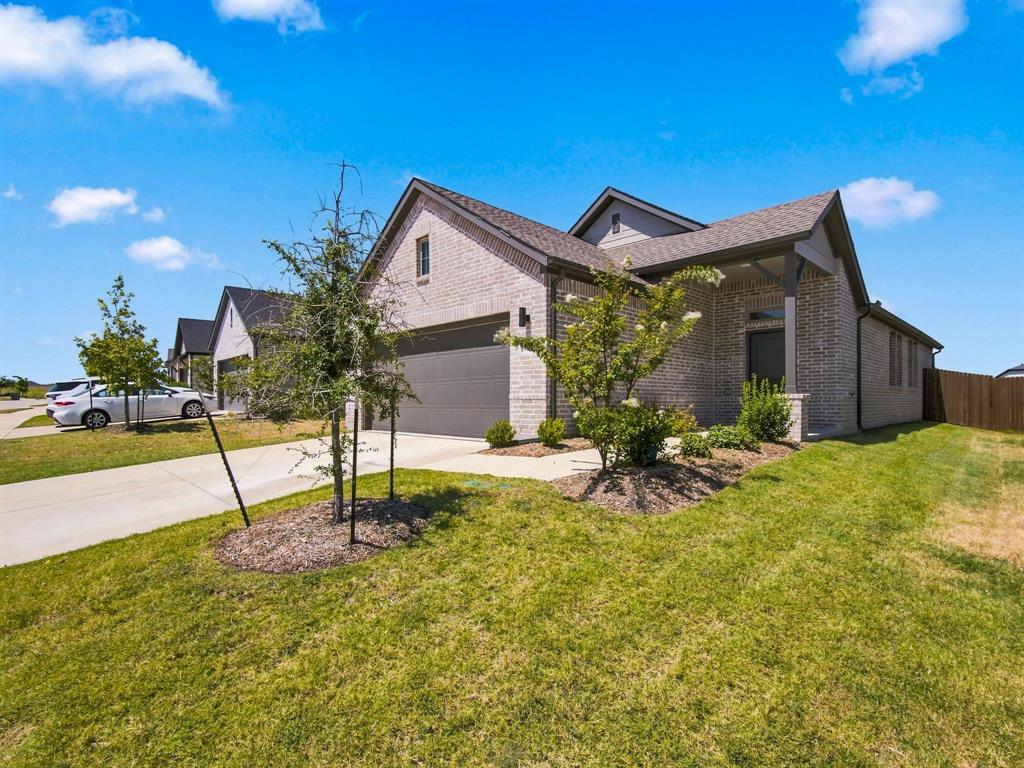Single-story residence featuring a brick exterior, gabled rooflines, attached two-car garage, concrete driveway, and landscaped front lawn