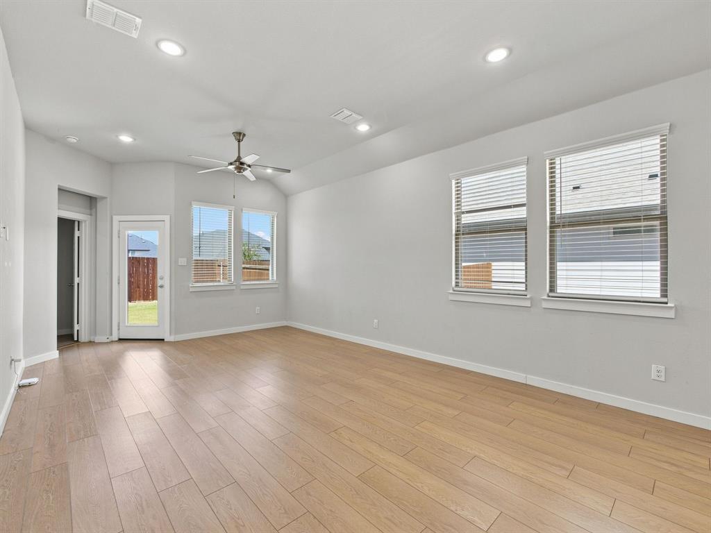 Vaulted ceilings featuring recessed lighting, a central ceiling fan, wood-finish flooring, and multiple windows providing natural light