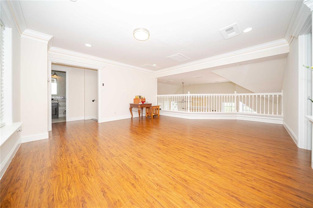 Open loft area featuring wood-finish flooring, crown molding, recessed lighting, and a white balustrade railing Open loft area featuring wood-finish flooring, crown molding, recessed lighting, and a white balustrade railing