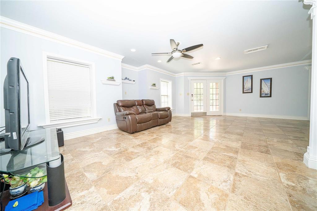 Large format stone tile flooring, crown molding, recessed lighting, ceiling fan, and French doors