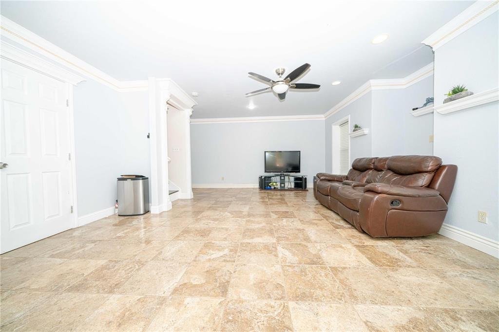 Large-format tile flooring, crown molding, recessed lighting, ceiling fan with integrated light fixture, and built-in wall shelving