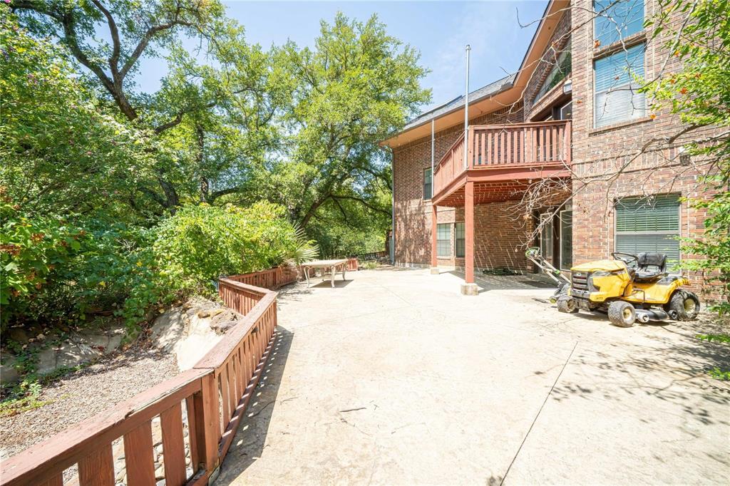 Brick exterior featuring a multi-level wood deck, concrete patio, and fenced perimeter