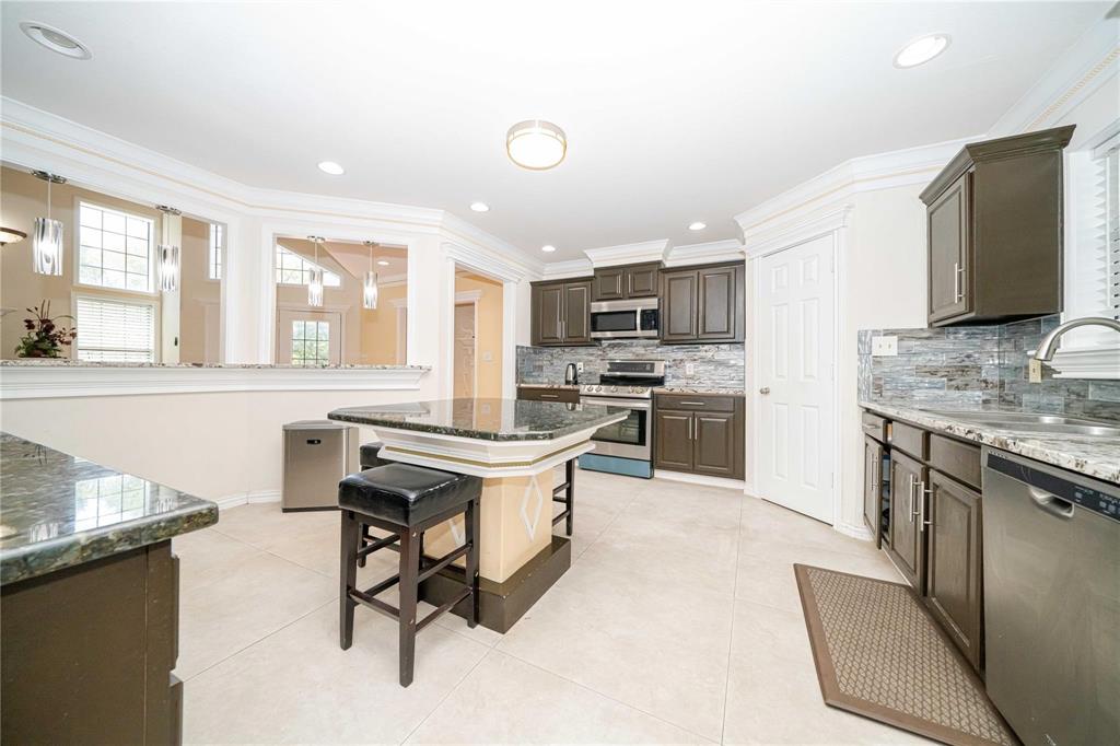 Kitchen featuring dark-finish cabinetry, stone countertops, central island, tiled flooring, and stainless steel appliances Kitchen featuring dark-finish cabinetry, stone countertops, central island, tiled flooring, and stainless steel appliances