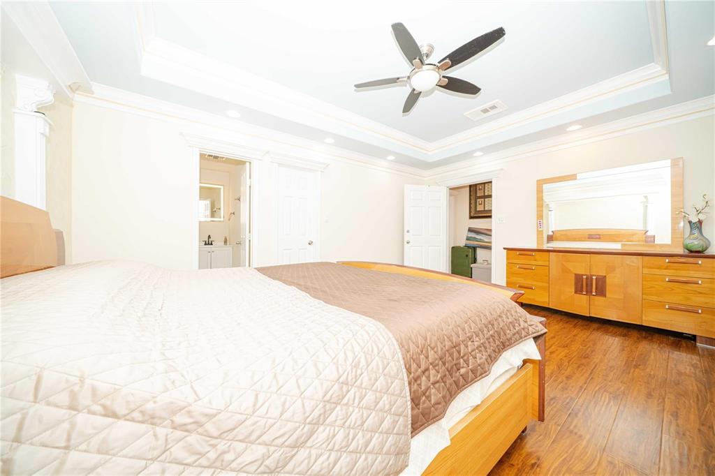 Tray ceiling with recessed lighting, wood-finish flooring, and ceiling fan with integrated light fixture