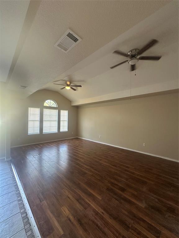 Vaulted ceiling featuring dual ceiling fans, wood-finish flooring, and arched window detailing Vaulted ceiling featuring dual ceiling fans, wood-finish flooring, and arched window detailing
