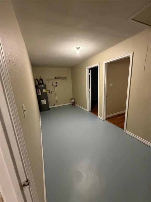Utility area featuring a water heater, built-in wire shelving, and finished painted flooring
