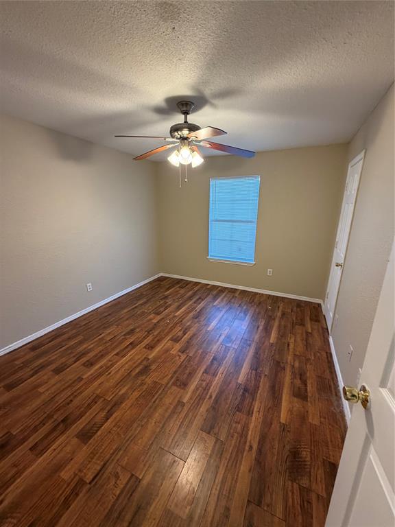 Interior space featuring wood-finish flooring, a neutral wall palette, a multi-blade ceiling fan with integrated lighting, and a single-hung window