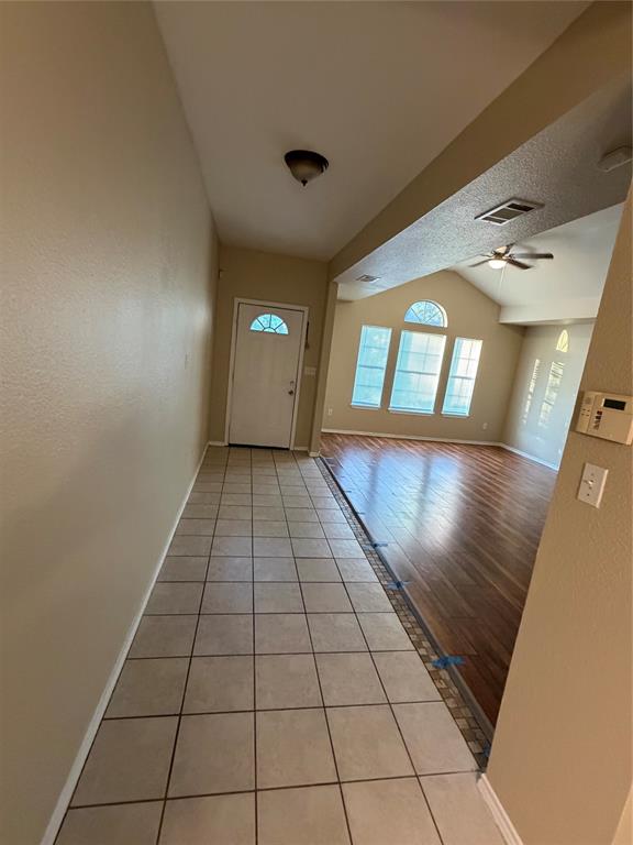 Entryway featuring square ceramic tile flooring, wood-finish flooring, vaulted ceilings, and multi-pane windows including an arched top transom Entryway featuring square ceramic tile flooring, wood-finish flooring, vaulted ceilings, and multi-pane windows including an arched top transom