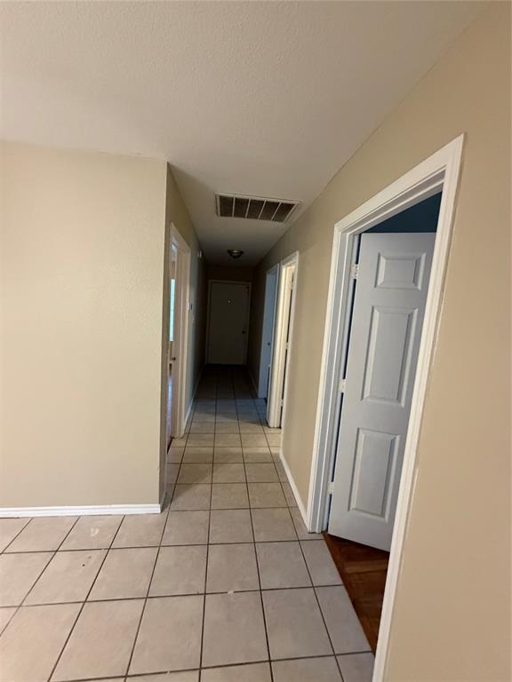 Neutral-toned interior hallway featuring large-format ceramic tile flooring, solid-core interior doors, and crisp white trim