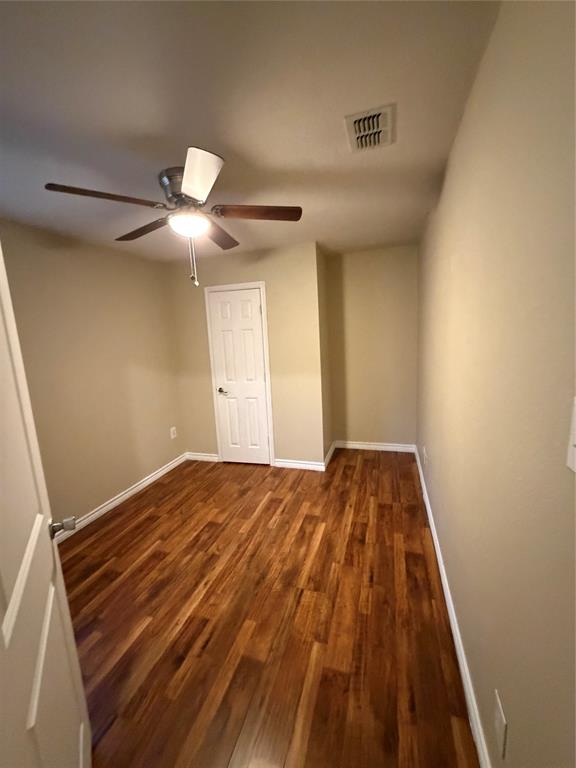 Room featuring wood-finish flooring, a ceiling fan with integrated lighting, and a six-panel door