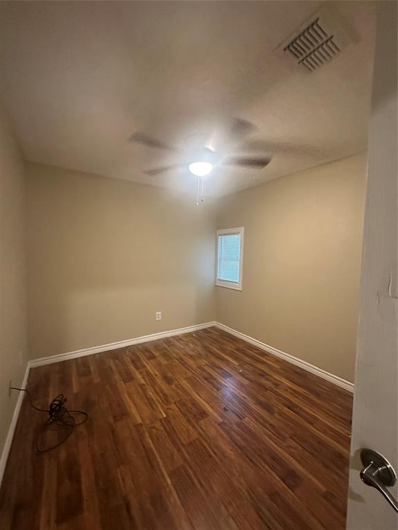 Room featuring wood-finish flooring, a neutral wall color, and a ceiling-mounted fan with integrated lighting Room featuring wood-finish flooring, a neutral wall color, and a ceiling-mounted fan with integrated lighting