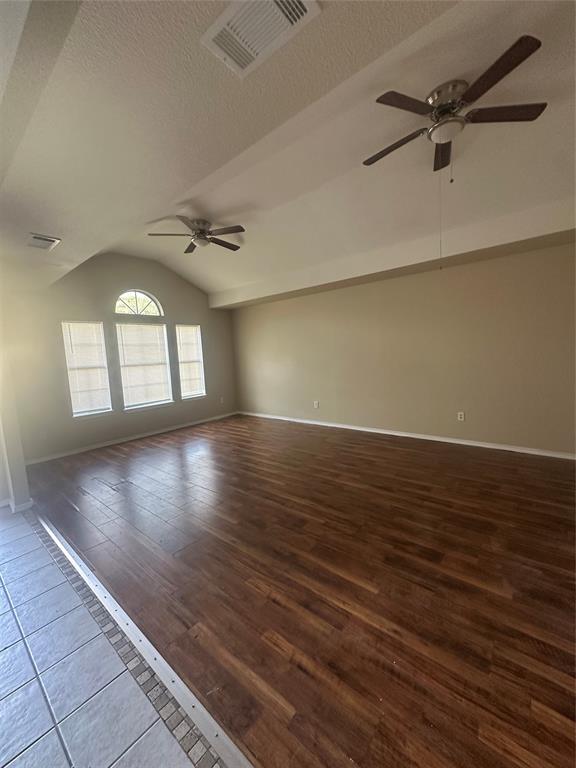 Vaulted ceilings, wood-finish flooring, two ceiling fans, and an arched transom window Vaulted ceilings, wood-finish flooring, two ceiling fans, and an arched transom window
