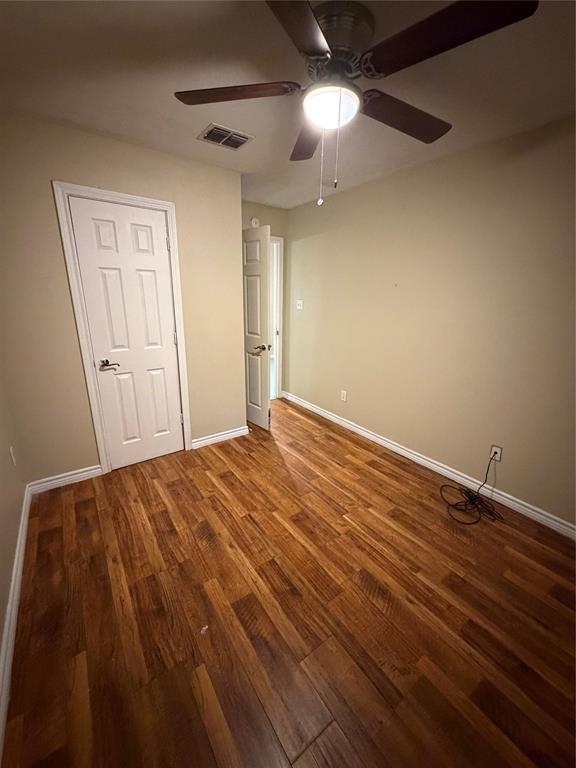 Wood-finish flooring, neutral wall tones, multi-panel interior doors, and a ceiling fan with integrated lighting