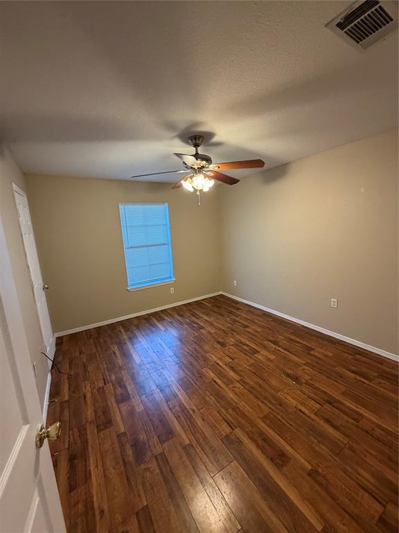 Interior room featuring wood-finish flooring, a single window, and a central ceiling fan with integrated light fixture