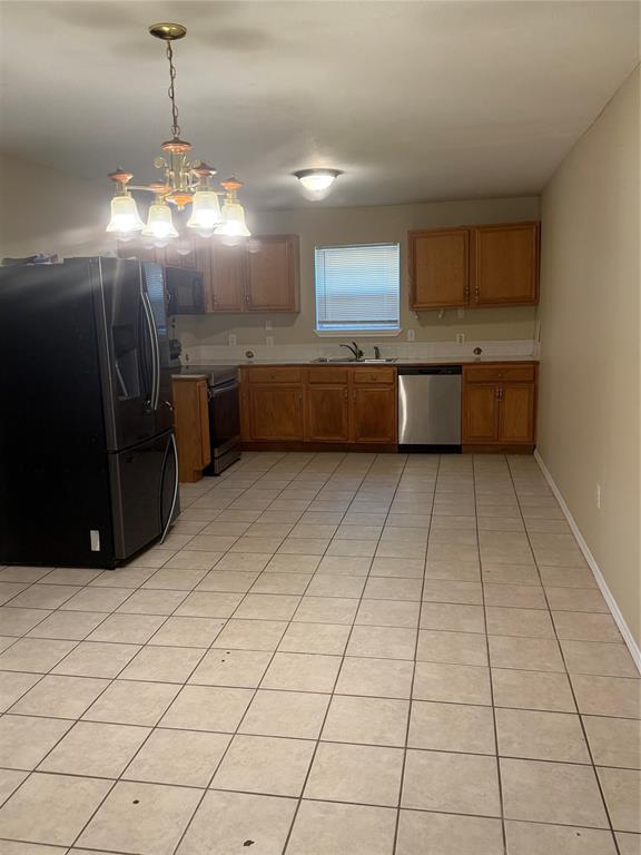 Kitchen featuring wood cabinetry, stainless steel dishwasher, ceramic tile flooring, and a multi-light hanging chandelier Kitchen featuring wood cabinetry, stainless steel dishwasher, ceramic tile flooring, and a multi-light hanging chandelier