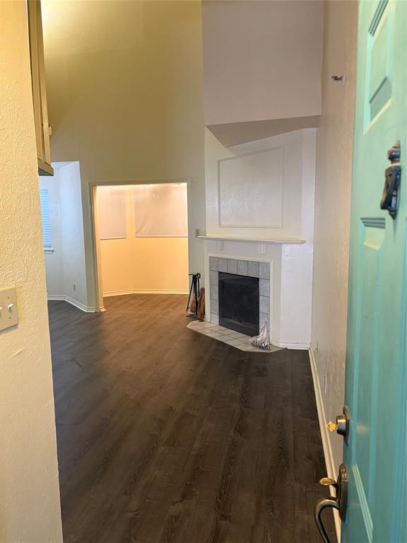 Entryway featuring high vaulted ceilings, wood-finish flooring, and a fireplace with a tile surround and mantel