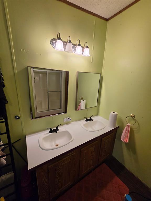 Dual-basin vanity featuring integrated sinks, laminate countertop, wood-finish cabinetry, and matte black hardware, accompanied by two wall-mounted mirrors and a four-light fixture Dual-basin vanity featuring integrated sinks, laminate countertop, wood-finish cabinetry, and matte black hardware, accompanied by two wall-mounted mirrors and a four-light fixture