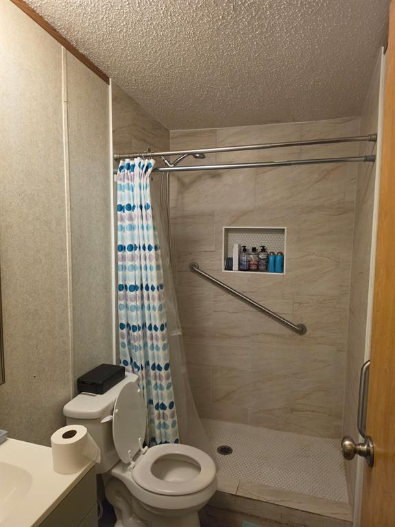 Walk-in shower featuring light-toned ceramic wall tile, mosaic floor tile, built-in recessed niche, and an installed metal grab bar Walk-in shower featuring light-toned ceramic wall tile, mosaic floor tile, built-in recessed niche, and an installed metal grab bar