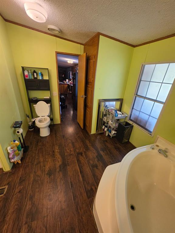 Bathroom featuring wood-finish flooring, a large soaking tub, and a window with a grid pattern Bathroom featuring wood-finish flooring, a large soaking tub, and a window with a grid pattern