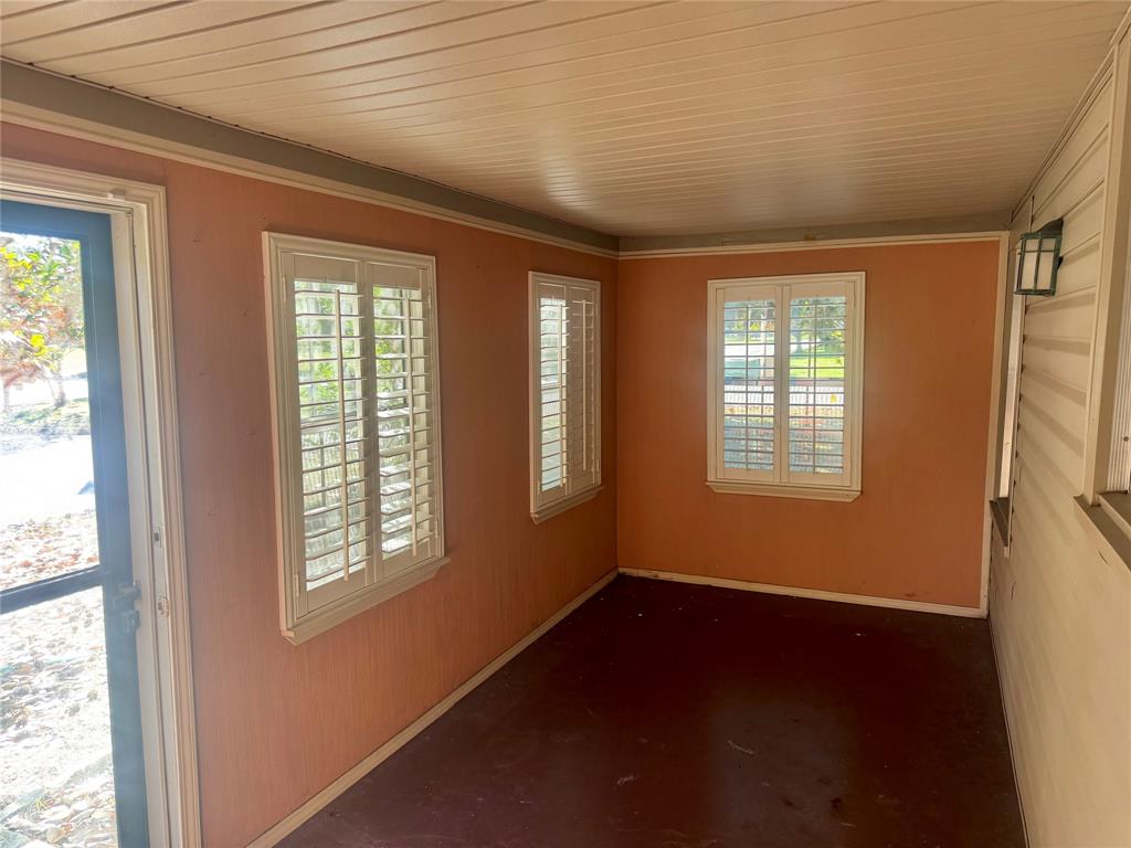 Enclosed porch featuring beadboard ceiling, plantation shutters, wall-mounted light fixture, and solid-surface flooring