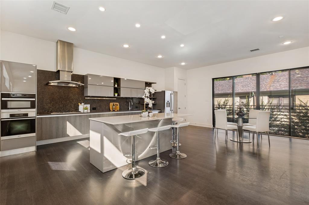 Kitchen featuring high-gloss cabinetry, stone-finish countertops, stainless steel wall-mounted oven and microwave, recessed lighting, and wood-finish flooring