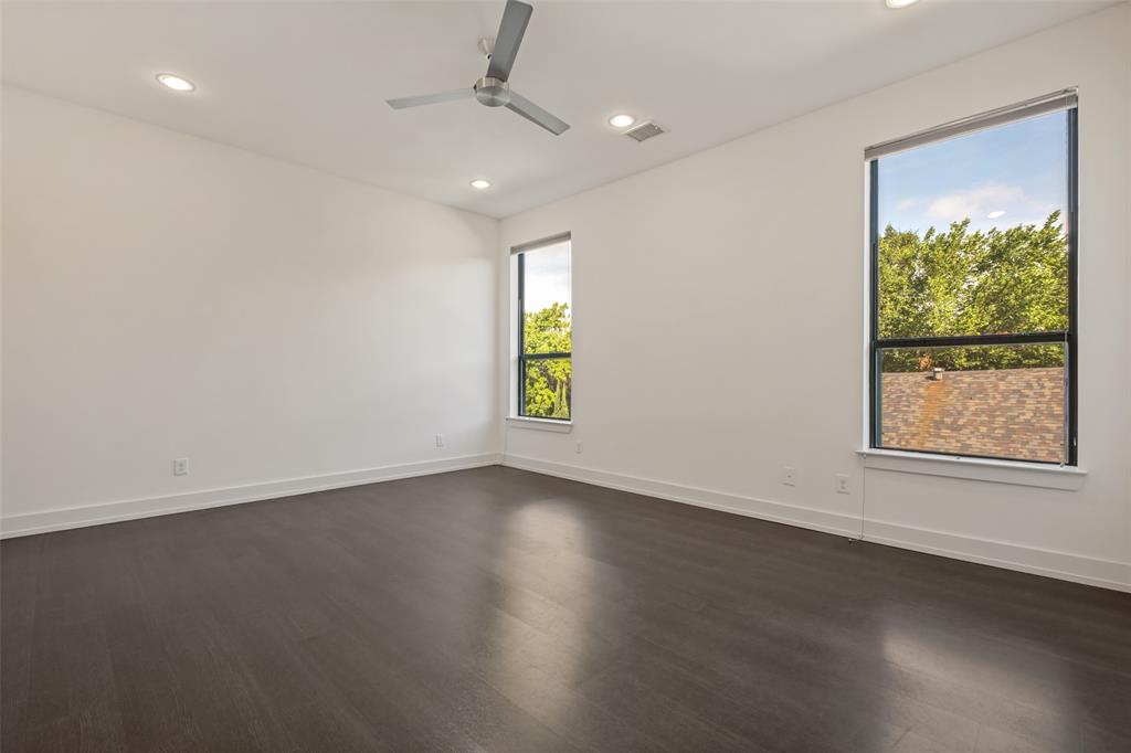 Spacious room featuring high ceilings, dark wood-finish flooring, recessed lighting, a modern ceiling fan, and large windows with black frames