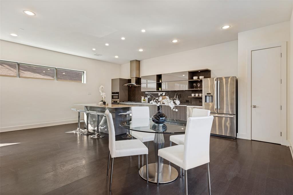 Contemporary kitchen featuring dark wood-finish cabinetry, a waterfall-edge stone island, recessed ceiling lighting, horizontal clerestory windows, and stainless steel appliances
