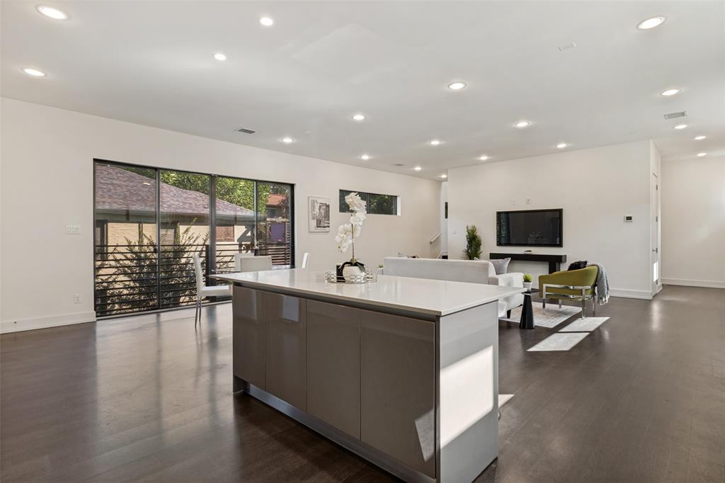 Open floor plan featuring wood-finish flooring, recessed lighting, and a central kitchen island with a stone countertop
