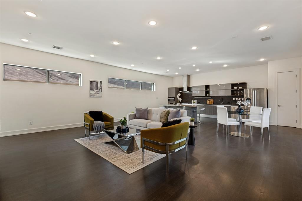 Open-concept interior featuring wood-finish flooring, recessed lighting, clerestory windows, and modern cabinetry with integrated stainless steel appliances