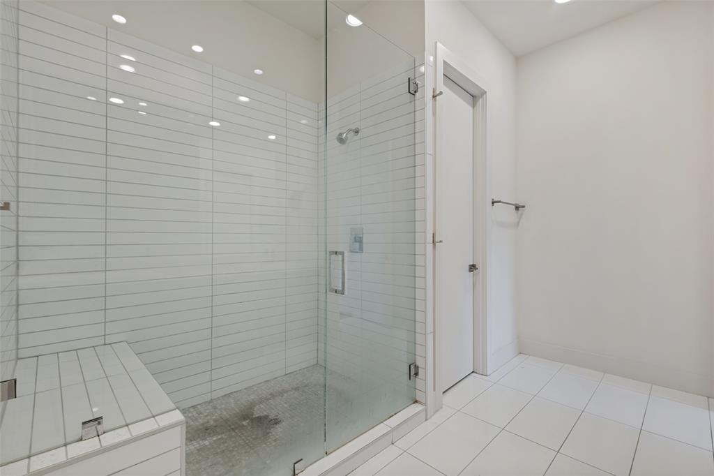 Walk-in shower featuring a frameless glass enclosure, built-in tiled bench, horizontal wall tile, and recessed lighting