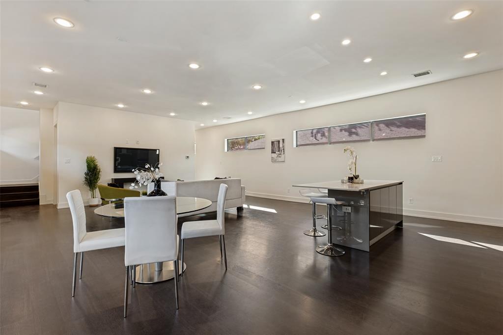Open-concept interior featuring wood-finish flooring, recessed lighting, horizontal clerestory windows, and a central island with a stone-top surface