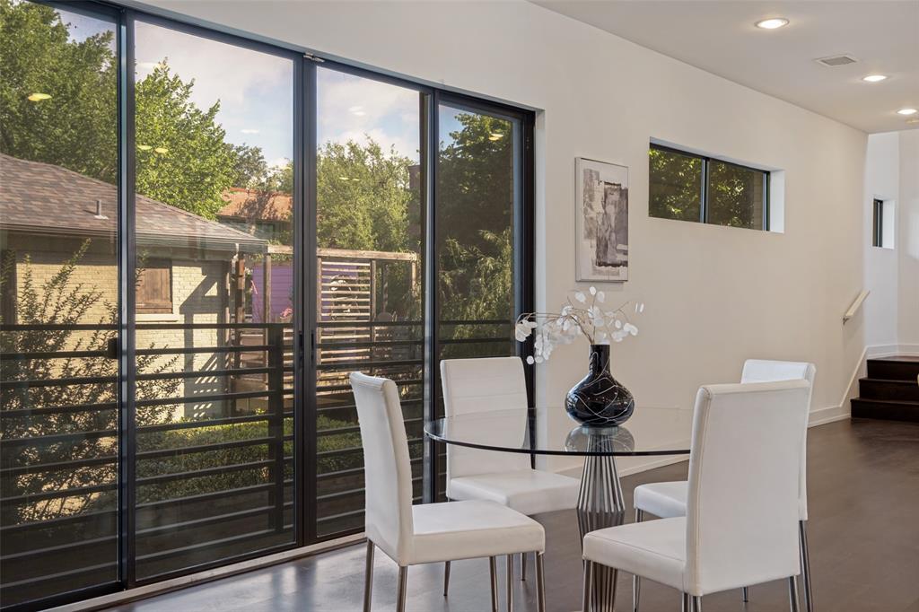 Floor-to-ceiling multi-panel sliding glass doors with dark frames, recessed lighting, dark wood-finish flooring, and horizontal window placement