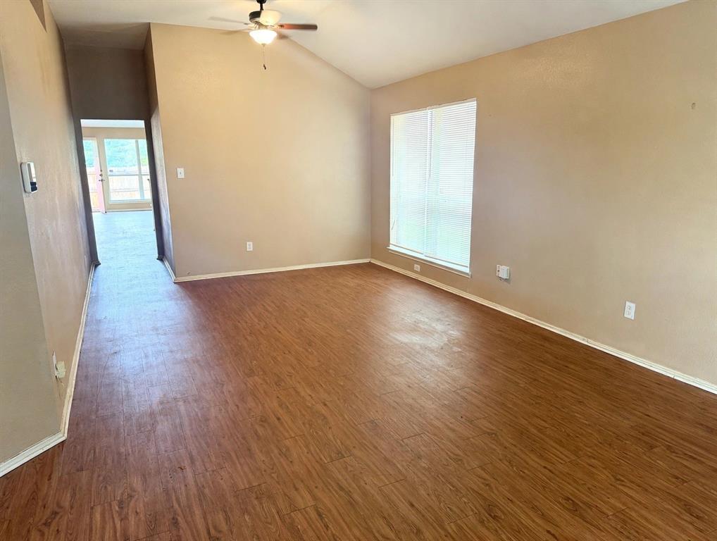 Vaulted ceilings, wood-finish flooring, and a large window with neutral wall finishes and a ceiling-mounted light fixture Vaulted ceilings, wood-finish flooring, and a large window with neutral wall finishes and a ceiling-mounted light fixture