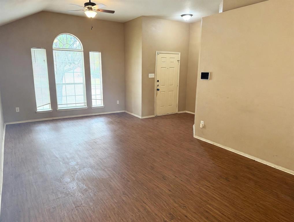 Vaulted ceiling featuring an arched window configuration, wood-finish flooring, and a ceiling fan with light fixture Vaulted ceiling featuring an arched window configuration, wood-finish flooring, and a ceiling fan with light fixture